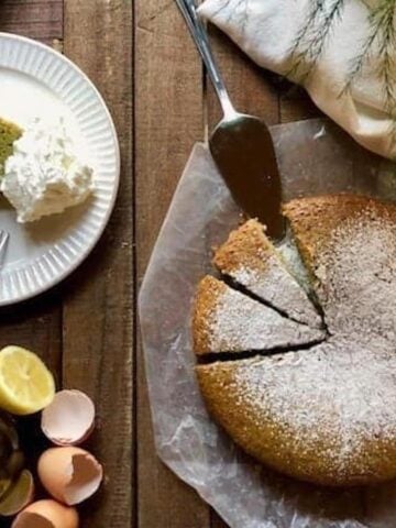 Basil olive oil cake on the counter sliced up with a slice on a plate.