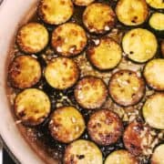 Zucchini slices in a pan with brown butter and minced garlic on top.