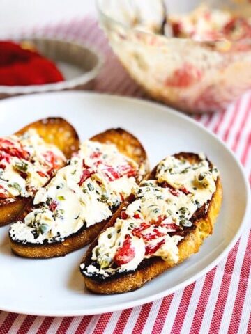 Crostini with goat cheese spread on top on a large plate.