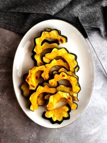 Roasted acorn squash slices on a plate.