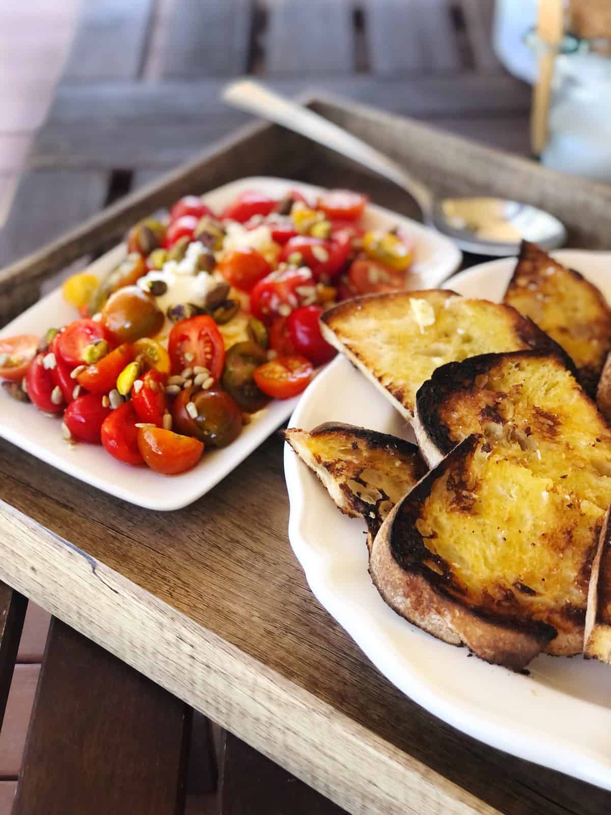 Tomato and ricotta salad on a table with bread on the side.