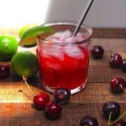 Homemade cherry limeade in a glass with ice.